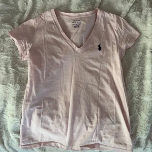 Ljusrosa t-shirt från Polo Ralph Lauren - Säljer en ljusrosa t-shirt från Polo Ralph Lauren med v-ringning, knappt använd. Passar superbra till sommaren💖
