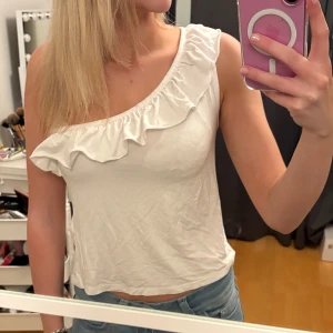 Vit volangtopp  - En söt och sommrig snedskuren vit volang topp från Gina Tricot. Använd ett fåtal gånger och säljer pga inte använt på flera år. 