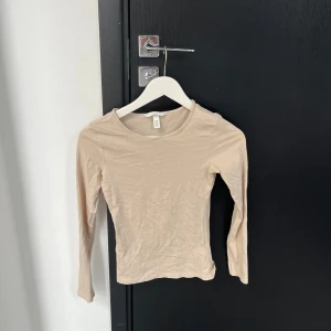 Beige långärmad topp - Säljer en stilren beige långärmad topp. Perfekt för lager-på-lager eller som den är. Enkel och mångsidig design som passar till det mesta. Skön och mjuk att ha på sig.