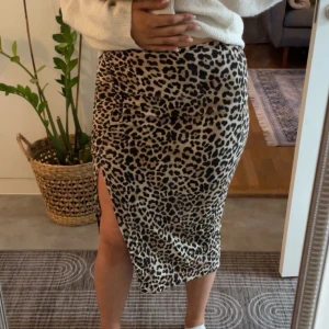 Leopardmönstrad kjol med slits - Leopardmönstrad kjol med slits på sidan. Kjolen har en tight passform. Den är i en bekväm längd och passar bra till både stickade tröjor och toppar.