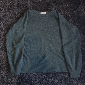 Grön kashmirtröja 100% - Säljer en mjuk och stilren grön tröja i 100% kashmir. Tröjan har en klassisk design med långa ärmar och ribbade kanter vid ärmslut och nederkant. Perfekt för att hålla sig varm och bekväm under kyliga dagar🥵🥶Nypriset ligger runt 3000kr och mitt pris är endast 749kr🍾🎉Tröjan har inga defekter alls.