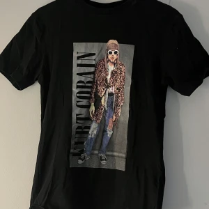 Svart t-shirt med tryck - Cool svart T-shirt med tryck av Kurt Cobain, Nirvana. Den är i bra skick och nästan aldrig använd. Storlek xs men passar även s.