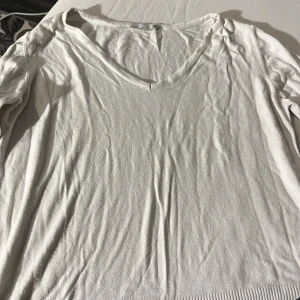 Vit v-ringad tröja - Säljer en stilren vit tröja med v-ringning. Perfekt för en avslappnad look. Tröjan har långa ärmar och är tillverkad i ett mjukt material som känns skönt mot huden. Passar bra till både jeans och kjol.