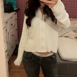 Vit hoodie med dragkedja - Säljer en vit hoodie med dragkedja framtill. Den har långa ärmar och en croppad design som ger en modern look. Perfekt för en avslappnad stil.