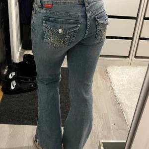 Low waist jeans - Snygga blå bootcut jeans med broderade detaljer på bakfickorna. De har en lågmidjad passform, Väldigt bra skick och lite stretchiga. Vintage h&m. Midjemått rakt över 35 cm. Innerbenslängd: 75cm