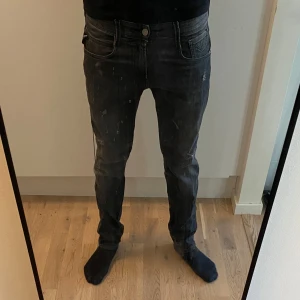 Svarta replay jeans med slitningar - Snygga svarta replay jeansbyxor med en slim passform. De har en klassisk femficksdesign och knappar i midjan. Perfekta för en stilren look. Säljer för att jag inte använder de längre. Köpta för 1299
