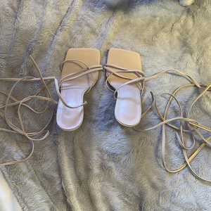 Beige sandaler med klack och knytband - Snygga beige sandaler med klack och långa knytband som ger en elegant look. De har en fyrkantig tå och är perfekta för att lyfta din outfit.
