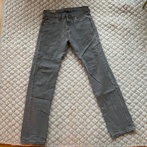 Grå Levis 501 jeans - Snygga grå Levis 501 jeans i klassisk design. De har en rak passform och är tillverkade i slitstarkt denim. Perfekta för en stilren look. Midjemått är W30 och längd L32. Använd typ två gånger. Nypris 1200