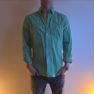 Ralph Lauren Grön rutig skjorta - Snygg grön rutig skjorta med långa ärmar och klassisk krage. Perfekt för en stilren look. Skjortan har knappar framtill och en diskret broderad logga på bröstet.