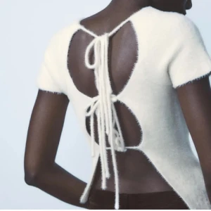 Vit stickad topp med öppen rygg - Säljer en stilren vit stickad topp med korta ärmar och en snygg öppen rygg. Helt ny 