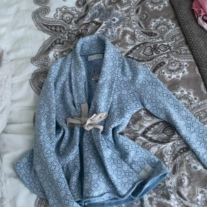 Blå blus från Odd Molly - Säljer en superfin blå blus från Odd Molly med ett snyggt geometriskt mönster. Koftan har en knytning framtill och långa ärmar. Perfekt för att hålla sig varm och stilren. Passar perfekt till både jeans och kjol!