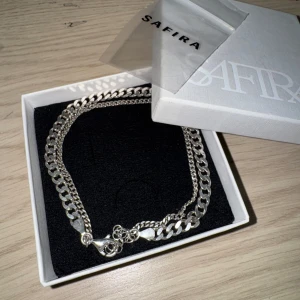 Äkta silver ankel smycke från Safira - Äkta silver kedja till ankel från Safira med en klassisk kedjedesign. Perfekt för att ge en stilren touch till din outfit. Levereras i en snygg förpackning. Original pris 1000kr