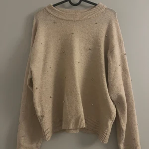 Gammel-rosa tröja med pärlor - Säljer en mysig gammel-rosa tröja dekorerad med små pärlor. Tröjan har långa ärmar och ribbade kanter vid hals, ärmslut och nederkant. Perfekt för en stilren och elegant look.