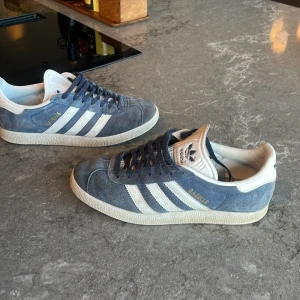 Blå Adidas Gazelle sneakers - Säljer ett par klassiska Adidas Gazelle sneakers i blå mocka och i bra skick, jag säljer dom därför att dom har blivit för små. Jag köpte dom för 1500kr