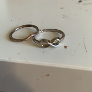 Två silverringar med oändlighetssymbol - Säljer två stilrena silverringar. Den ena ringen har en elegant oändlighetssymbol som detalj. Perfekta för att bära tillsammans eller var för sig för en minimalistisk look.