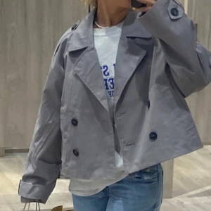 Grå kavaj med knappar - Snygg grå kavaj med stora knappar och en avslappnad passform. Perfekt för en stilren look. Den har långa ärmar och en klassisk krage.