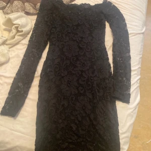 Svart spetsklänning från NLY One - Elegant svart kort klänning i spets från NLY One. Den har en tight passform och långa ärmar, perfekt för en stilfull kväll. Klänningen har ett vackert spetsmönster som ger en lyxig känsla. Använd 5ggr bara 
