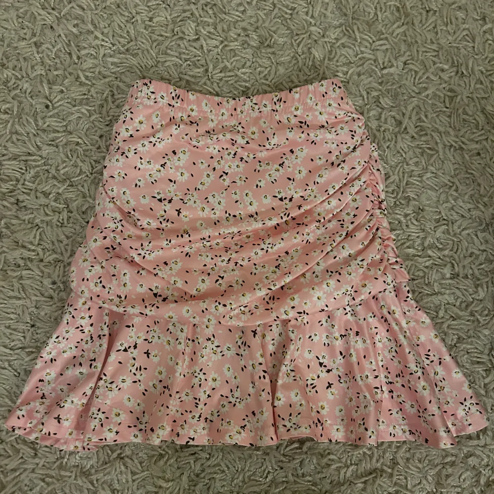 Söt rosa kjol med blommigt mönster och volangdetaljer. Perfekt för en somrig look. Kjolen har en kort längd och en smickrande passform. Lånade bilder!! Kjolen är aldrig använd! Fraktar endast varan och köparen betalar frakten! Priset som syns är vad som gäller🙏🫶. Hameet.