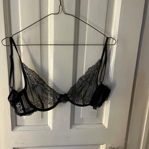 Svart spets-bh - Elegant svart bh i spets med justerbara axelband och en fin rosett framtill. Endast testad. Storlek 75B