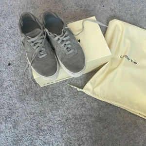 Grå sneakers från Axel Arigato - Snygga grå sneakers från Axel Arigato med klassisk snörning och stilren design. Perfekta för en avslappnad look. Skorna kommer med originalförpackning och påse. Priset kan sänkas