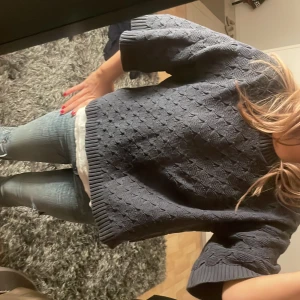 Mörkblå stickad tröja - Säljer en mysig mörkblå stickad tröja med trekvartsärm. Tröjan har ett diskret mönster och ribbade kanter vid ärmslut och nederkant. Perfekt för kyligare dagar.