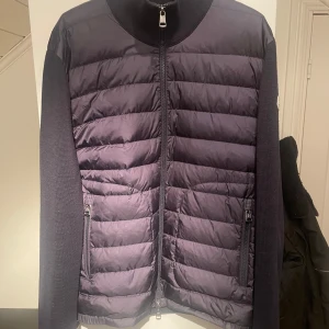  Moncler cardigan - Säljer en snygg marinblå cardigan från Moncler i mycket bra skick. Jackan är självklart äkta och har även kvitto på den för dom som vill se⭐️. Perfekt för höst och vinter, håller dig varm och stilren. Passar både till vardags och lite finare tillfällen. Storlek är L men sitter lite mindre. Vid frågor är det bara att höra av sig😁
