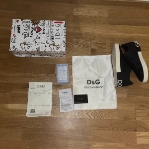Svarta sneakers från Dolce & Gabbana - Snygga svarta sneakers från Dolce & Gabbana med vit sula och logotyp på hälen. Skorna har snörning och är tillverkade i ett slitstarkt material med diskret mönster. Perfekta för en stilren look. 