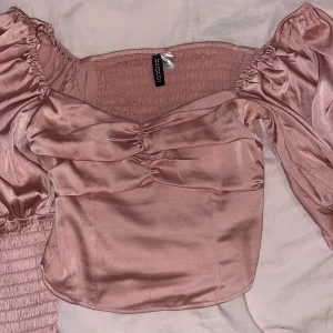 Rosa satinblus från H&M Divided - Säljer en rosa satinblus från H&M Divided. Blusen har puffiga ärmar och en smickrande rynkad detalj framtill. 
