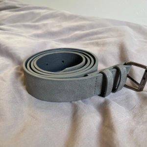 Grått mocka bälte  - Hej, jag säljer ett grått Mocka bälte i bra skick. Om ni har frågor så skicka. Strlk 100 cm