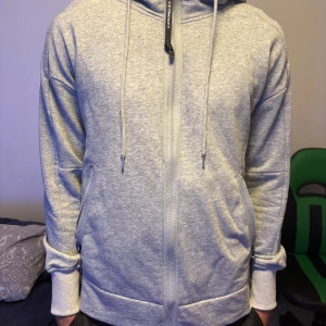 Grå hoodie från C.P. Company - Säljer en snygg grå hoodie från C.P. Company. Den har en dragkedjor till fickorna och googels i luvan. Väldigt skön och snygg att ha på sig. Säljer eftersom den knappt kommer till använding, om du har frågor så är det bara att skriva!