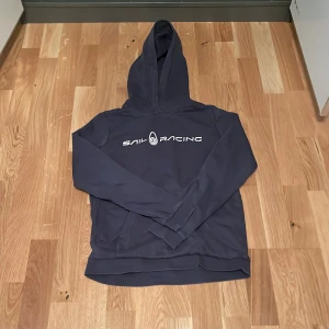 Sail Racing Hoodie  - Tja!!  Säljer en mörkblå💙 hoodie från Sail Racing med logga på bröstet. Tröjan har inte ablivit använd på ett tag så jag säljer den. Perfekt för en avslappnad stil. Hör av er vid minsta fråga eller prisförslag. 🙌🏼