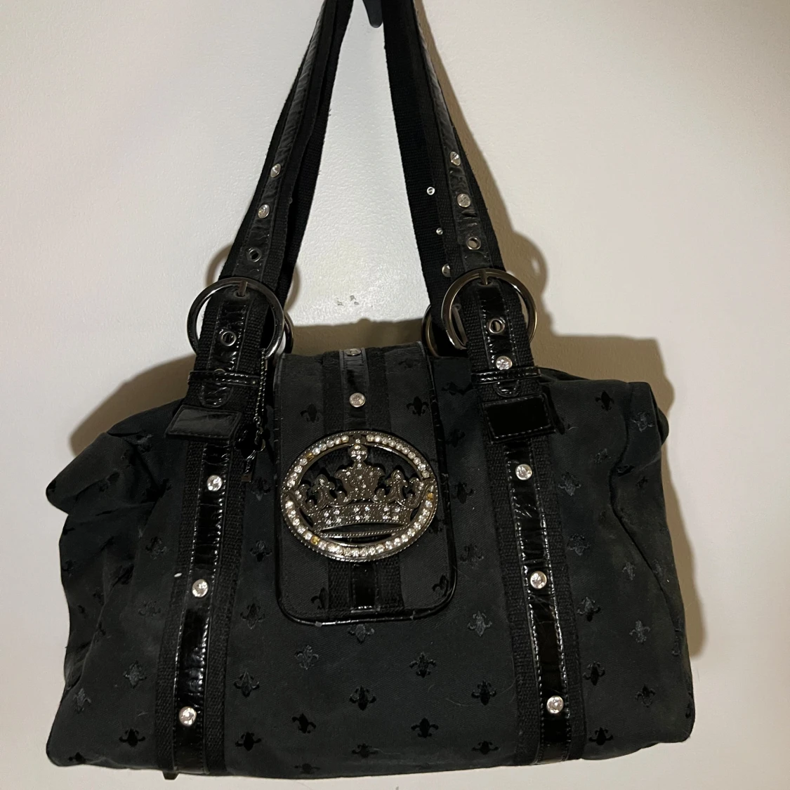 Svart axelväska med dekorativt emblem