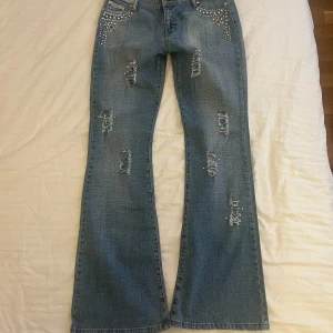 Lågmidjade utsvängda jeans  - Snygga blå lågmidjade utsvängda jeans med coola detaljer i superbra skick, inga tecken på användning ❣️ Måtten finns bland bilderna men det som inte finns plats är grenmått: 24 cm och lårmått: 24 cm❣️