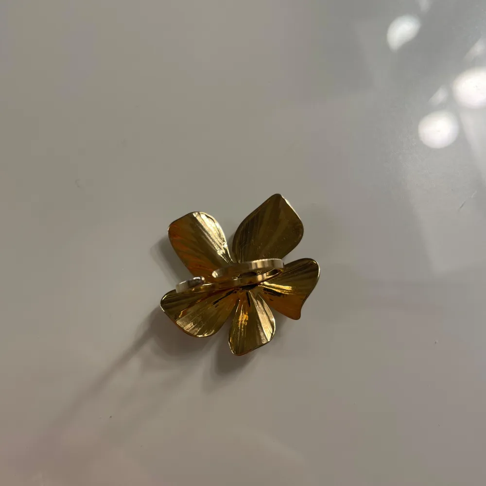 Säljer en superfin guldfärgad ring formad som en blomma. Den har detaljerade blad och en glittrig mitt som verkligen fångar ljuset. Kuster var och gjprd av rostfri stål. Ej några defekter förutom att 2 diamanter i mitten saknas men det märks inte. Asusteet.