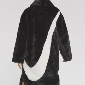 Svart pälsjacka med swosh märke baktill - Snygg och trendig svart pälsjacka med ett vitt swosh/nike märke på baksidan. Jackan har en lång passform och super mysig. Perfekt för vintern. Jackan är köpt för 2196kr och säljer den för 1000 då den aldrig är använd endast testad, Alltså HELT ny.