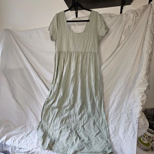 Grön gravid klänning med korta ärmar - Säljer en ljusgrön klänning med korta ärmar och rund halsringning. Klänningen har en avslappnad passform och är perfekt för varma dagar. Tillverkad i ett mjukt och bekvämt material. Djur och rökfritt hem. Tvättar parfymfritt.  Använd fåtal gånger. 