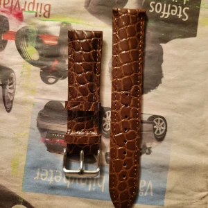 Brunt Aligator klockarmband - Snyggt brunt klockarmband i genuine aligator. Armbandet har en klassisk design med silverfärgat spänne och flera justeringshål för perfekt passform.                     Storlek 18 