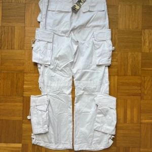 Vita cargobyxor från Charlotte Game - Säljer ett par vita cargobyxor från Charlotte Game. Byxorna har flera praktiska fickor och snörning vid bensluten. Perfekta för en avslappnad stil med en loose passform.