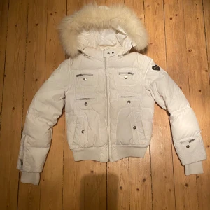 Vit Puffer jacket med pälsdetaljer - Säljer en snygg vit Puffer jacka från Canadian Classics med avtagbar huva och pälsdetaljer. Jackan har flera praktiska fickor med knappar och dragkedjor. Perfekt för kalla vinterdagar. Står storlek M men skulle säga att den är mer åt S hållet. Den har tyvärr en permanent fläck på baksida arm men syns inte så jätte mycket tycker jag. Dragkedjan är lite trög också så man måste se till att sätta i den hårt annars går den upp på jackan. 💋 Kontakta mig vid frågor eller intresse av köp ;)