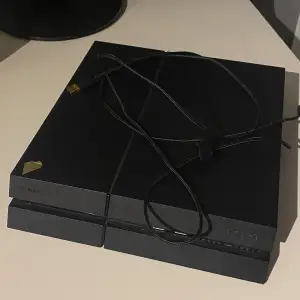 Säljer en svart PlayStation 4 med tre handkontroller. Två av kontrollerna är svarta och en har ett kamouflagemönster. Konsolen har två USB-portar på framsidan och kommer med en strömkabel. Skriv via intressen, pris kan diskuteras 