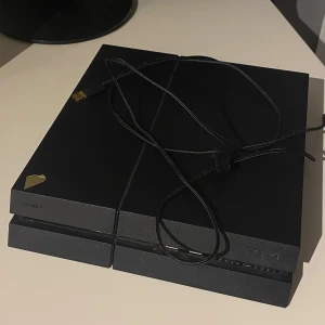 Svart PlayStation 4 med tre handkontroller - Säljer en svart PlayStation 4 med tre handkontroller. Två av kontrollerna är svarta och en har ett kamouflagemönster. Konsolen har två USB-portar på framsidan och kommer med en strömkabel. Skriv via intressen, pris kan diskuteras 
