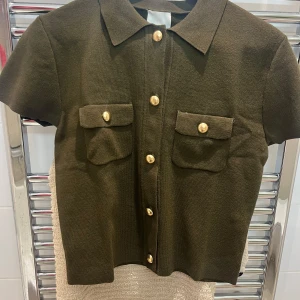 Olivgrön kortärmad skjorta med guldknappar - Ej använd och har prislapp på🥰Snygg olivgrön skjorta med korta ärmar och stiliga guldknappar. Skjortan har två praktiska bröstfickor med knappdetaljer. Perfekt för en chic och avslappnad look.