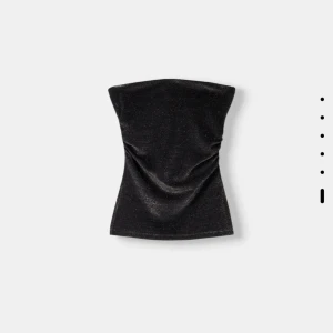 Svart glittrig tubtopp från Bershka - Snygg svart tubtopp från Bershka med glittrig yta. Perfekt för en kväll ute eller festliga tillfällen. Toppen är axelbandslös och har en figurnära passform. Aldrig använd, prislapp kvar!! Storlek S men passar absolut XS också.