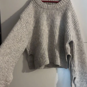 Grå ribbad stickad tröja från Gina Tricot - Mysig grå virkad/stickad tröja från Gina Tricot med ribbad design. Den har slits i slutet av tröjan men även i slutet av armarna. Köpt för 399kr men säljer endast för 150kr
