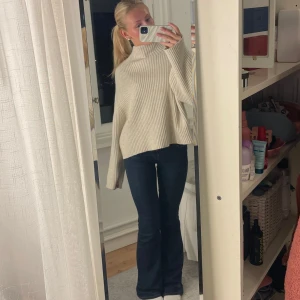 Stickad polotröja  - Säljer en stilren beige ribbad tröja med hög krage och långa ärmar. Tröjan har en loose passform och är perfekt för kyligare dagar. Den är både bekväm och trendig