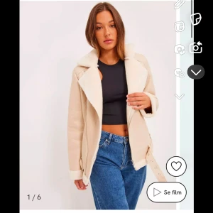 Beige jacka med pälsfoder - Snygg beige jacka med vit pälsfoder och dragkedjedetaljer. Jackan har en modern design med bälte i midjan och långa ärmar. Perfekt för kyligare dagar. Helt oanvänd, nypris 999