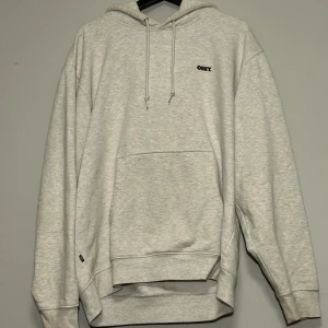 Grå hoodie från Obey - Grå Obey hoodie med logga fram och bak.