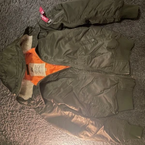 Grön bomberjacka från Alpha Industries - Säljer en grön bomberjacka från Alpha Industries i mycket bra skick. Jackan har en orange insida och en klassisk 'Remove Before Flight'-tag. Den är långärmad med dragkedja och ribbade muddar. Perfekt för vintern! Nypris: 2600 Mitt Pris: 1000‼️