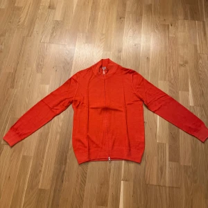 Orange kofta från Gran Sasso - Säljer en snygg orange kofta från Gran Sasso, tillverkad i Italien. Den har en dragkedja framtill och är perfekt för både höst och vår. Koftan är i mycket bra skick och passar perfekt för en stilren look. Nypris 2499kr skick 10/10