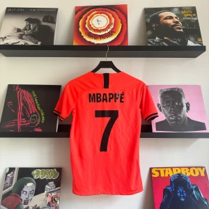 Mbappe tröja  - Säljer en snygg orange fotbollströja från Jordan med Mbappé och nummer 7 på ryggen. Tröjan har korta ärmar och är i mycket bra skick. Perfekt för fotbollsfans som vill ha något unikt! 🧡